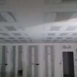 Construction intérieure avec plafond en placoplatre et poutres apparentes en cours de préparation pour peinture.