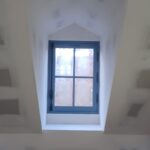 Fenêtre étroite verticale avec rebord intérieur en placoplatre dans une pièce sous construction éclairée naturellement